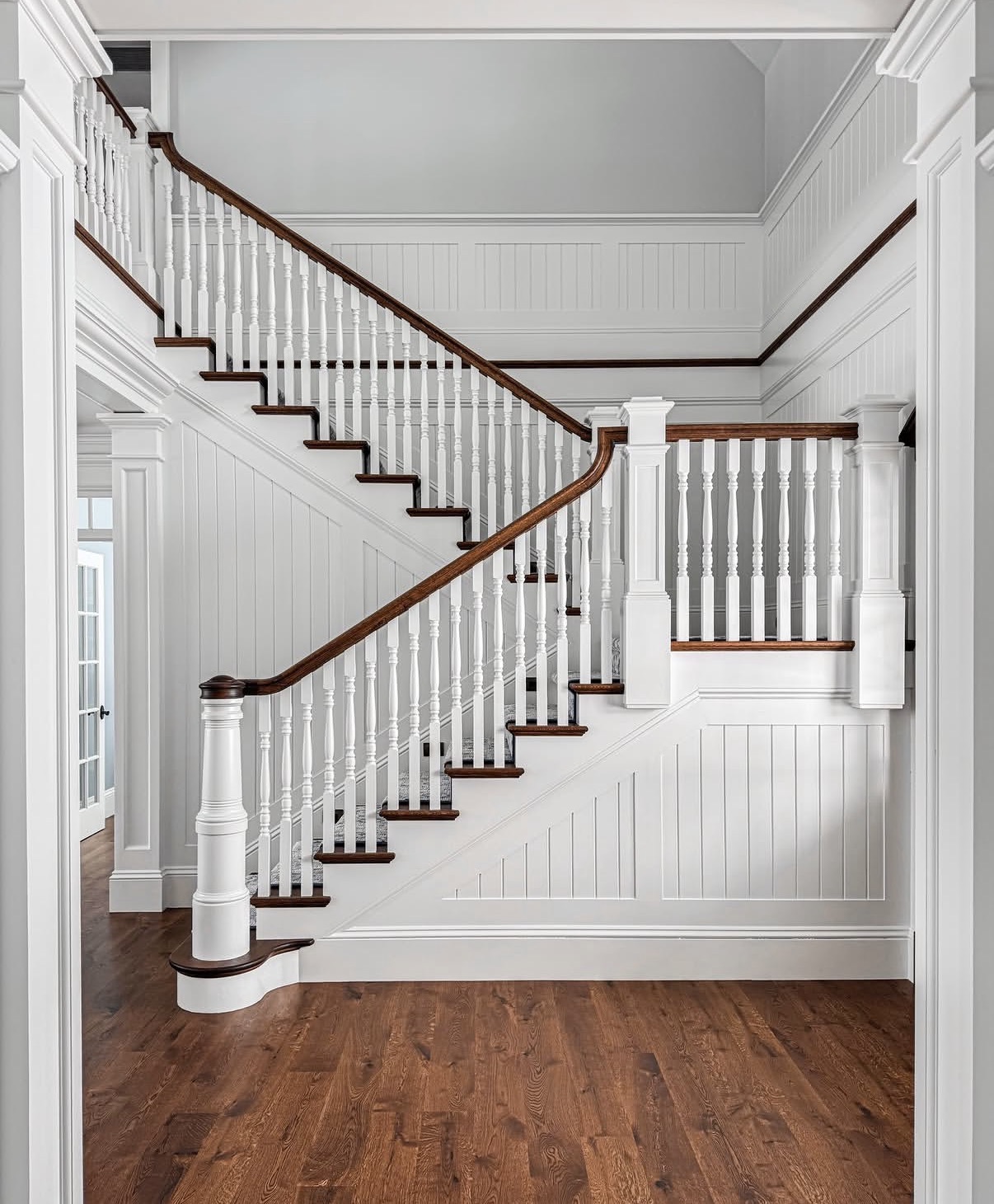 Grand staircase with detailed wainscoting and crown molding